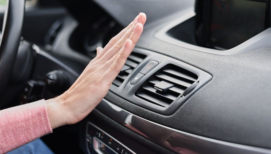 A person is touching the air vent in a car. | Import Specialty Service