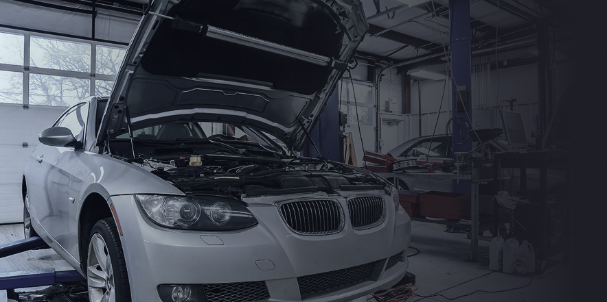 A silver car with its hood open is sitting in a garage. | Import Specialty Service