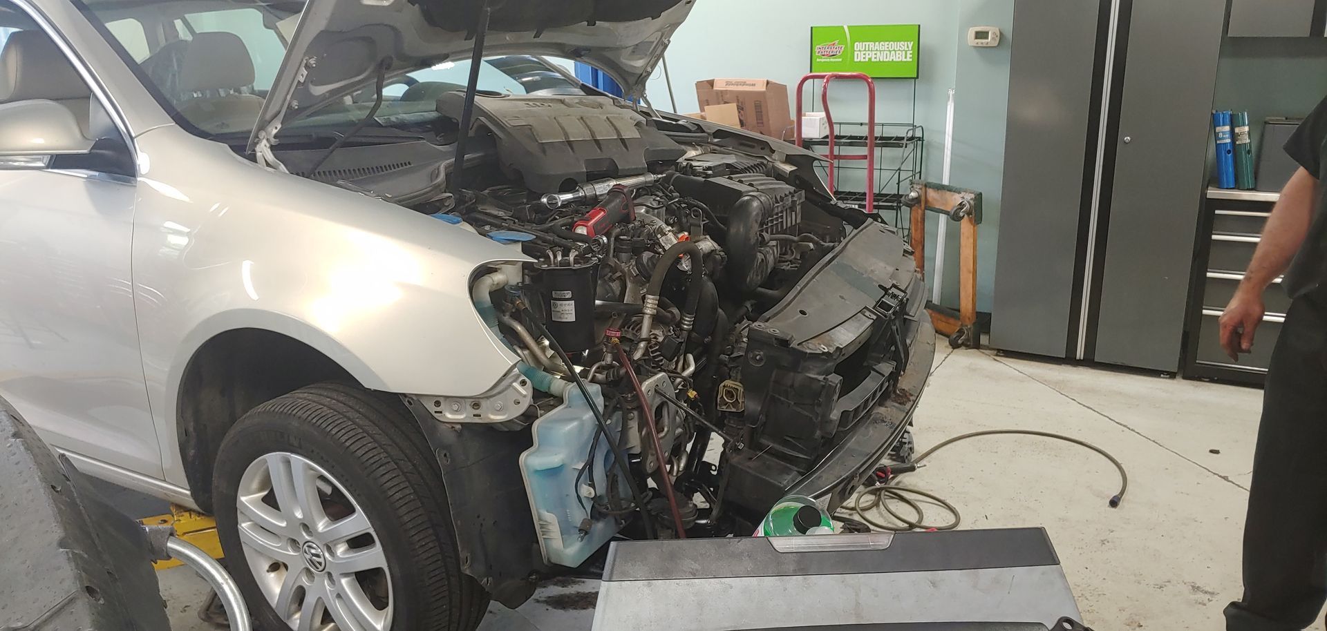 A car is being repaired in a garage with the hood open. | Import Specialty Service