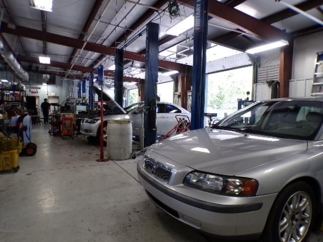 A silver car is parked in a garage with other cars | Import Specialty Service