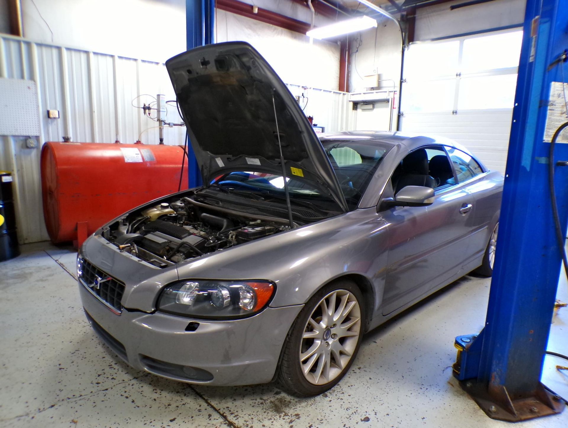 A car with the hood up is on a lift in a garage. | Import Specialty Service