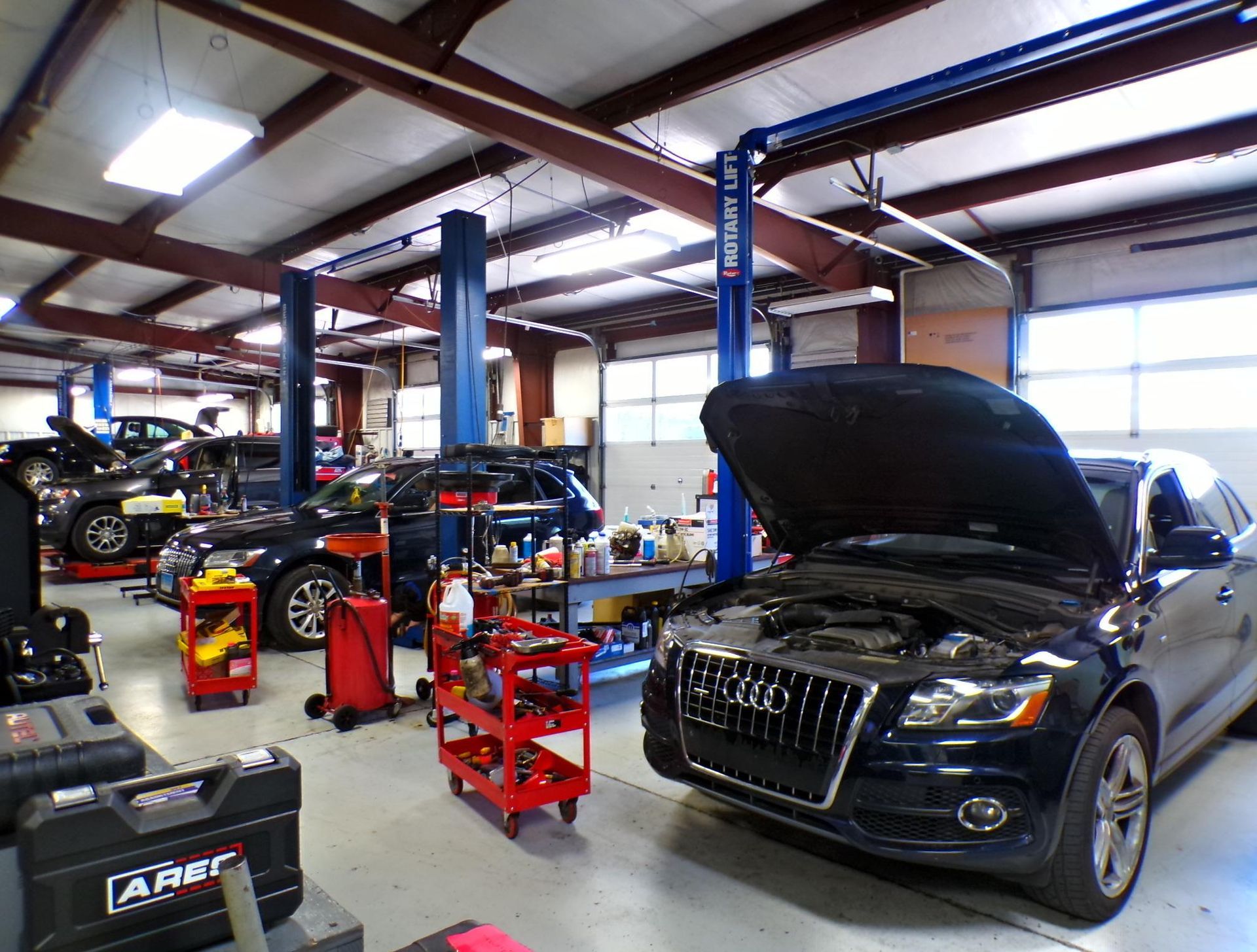 A black car with the hood up is in a garage. | Import Specialty Service