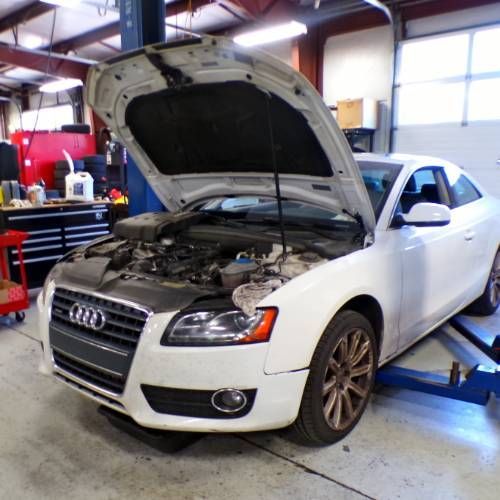 A white audi car with the hood open in a garage | Import Specialty Service