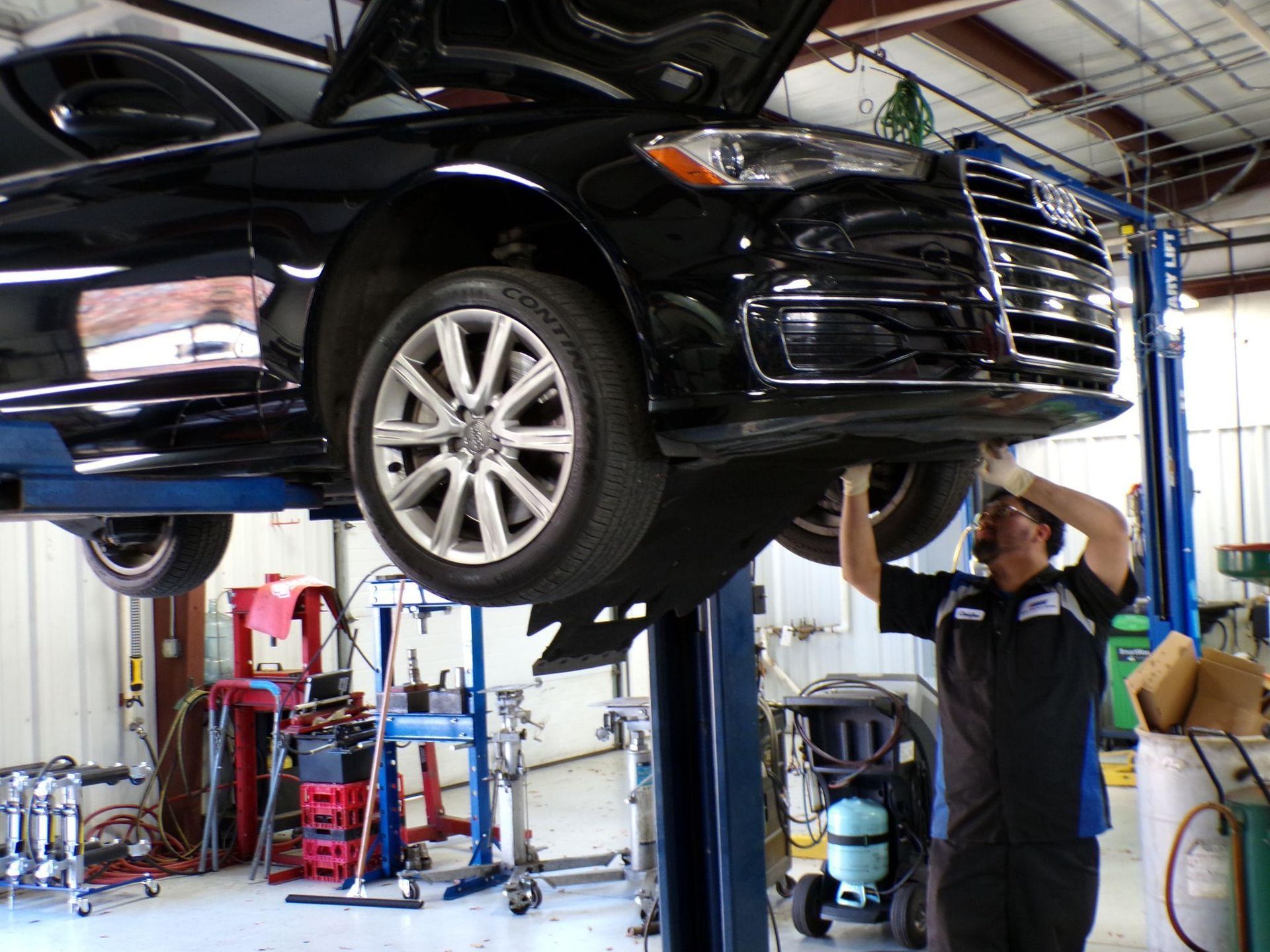 A man is working on a car on a lift in a garage. | Import Specialty Service