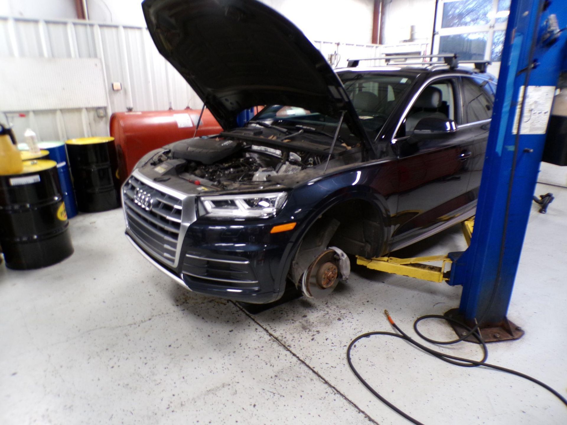 A car with the hood up is on a lift in a garage | Import Specialty Service