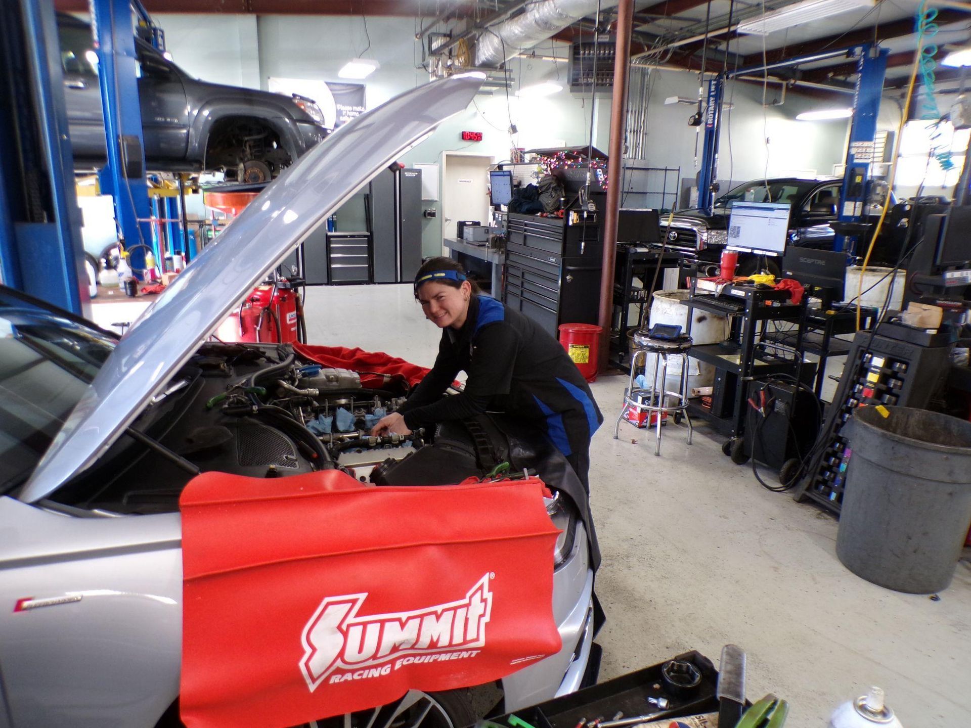 A man is working under the hood of a car in a garage | Import Specialty Service