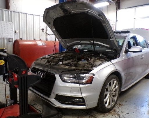 A silver car with its hood open in a garage. | Import Specialty Service