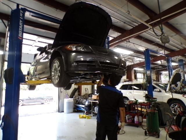 A car on a lift with the hood up in a garage | Import Specialty Service