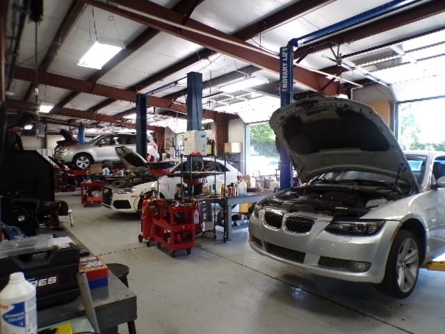A bmw is parked in a garage with its hood open | Import Specialty Service