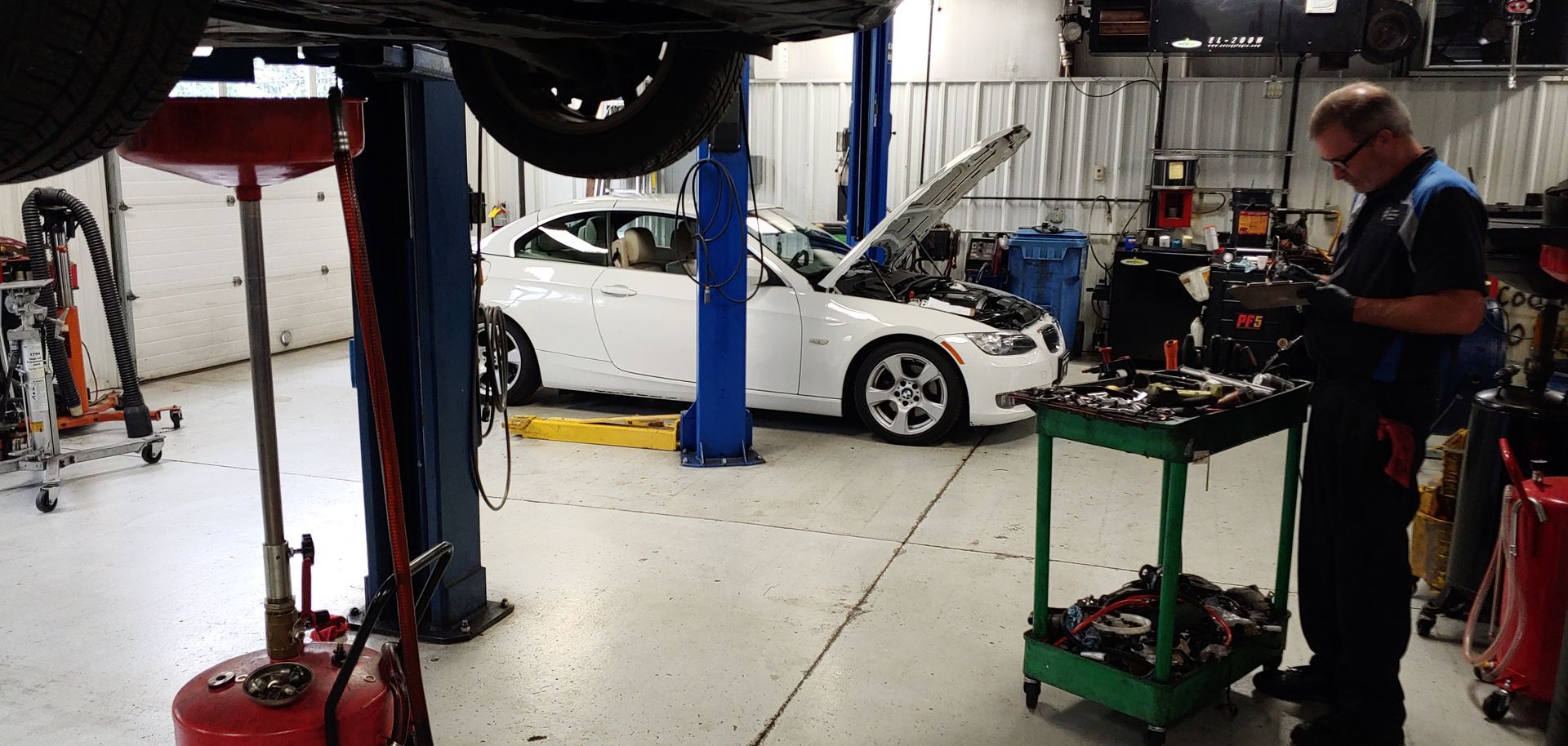 A man is working on a white car in a garage. | Import Specialty Service