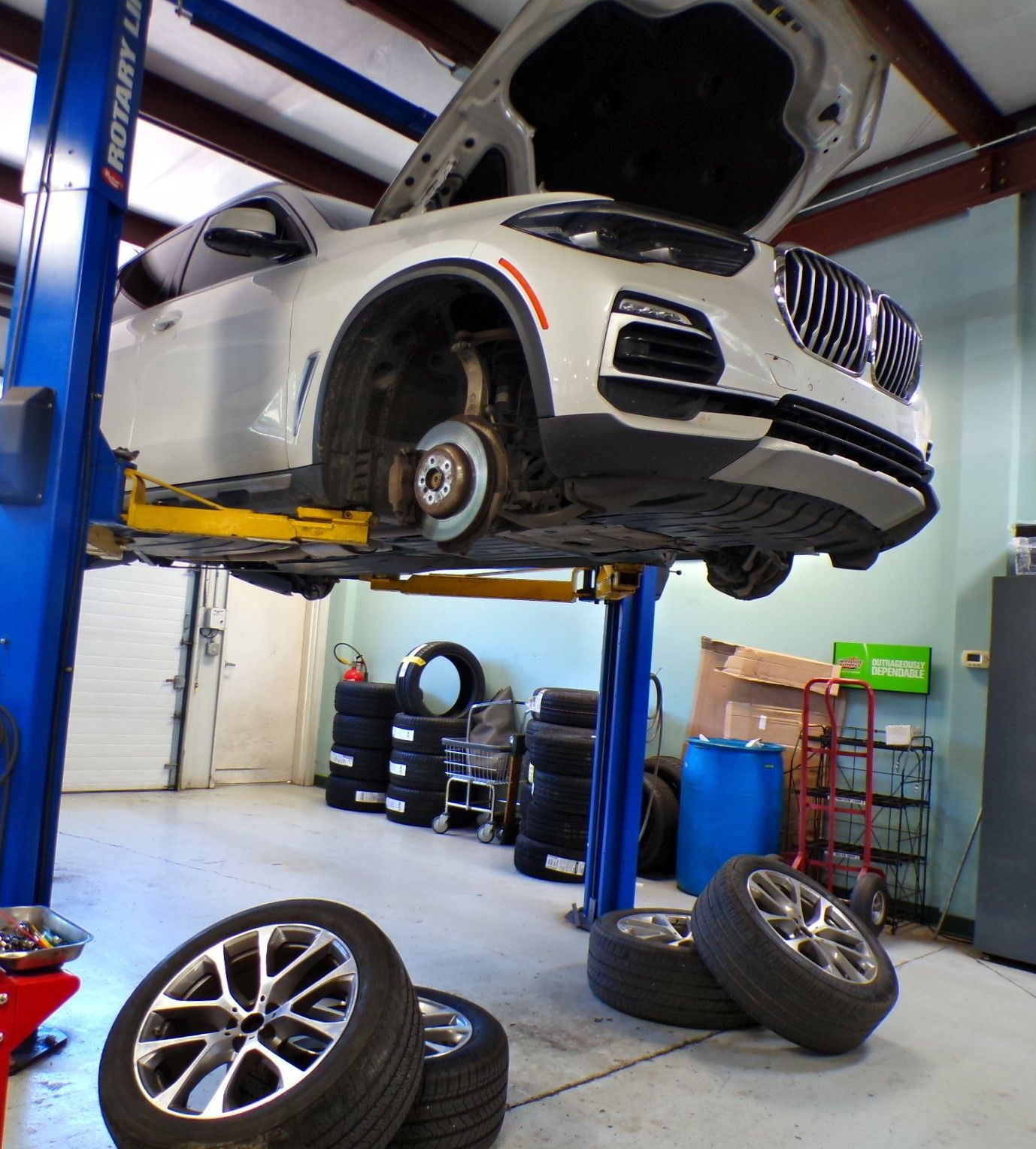 A car on a lift with the hood open in a garage | Import Specialty Service