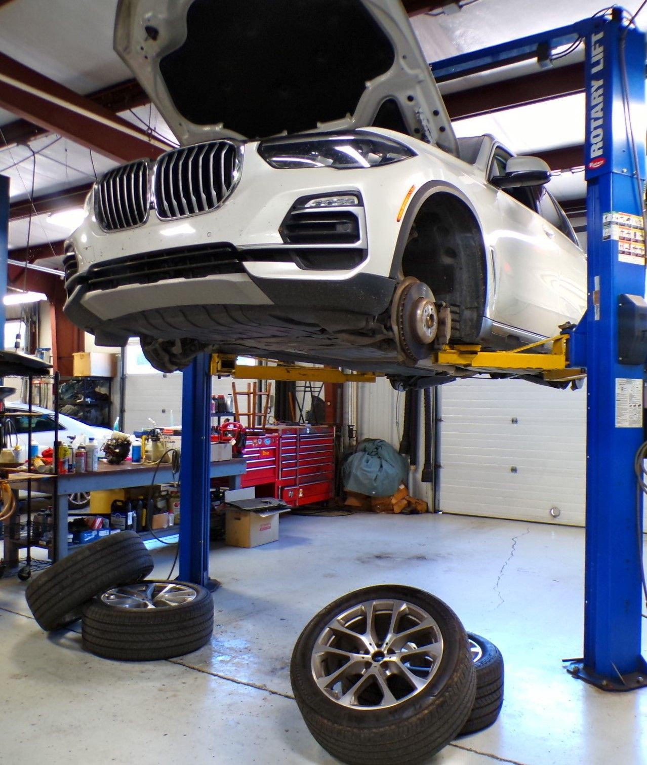 A white bmw is on a lift in a garage | Import Specialty Service