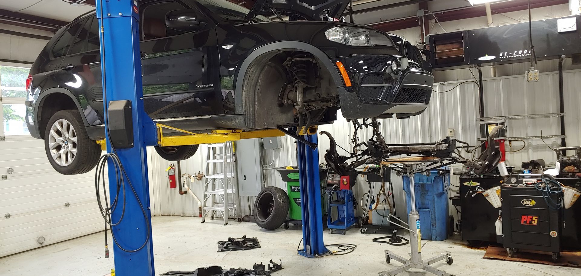A car is sitting on a lift in a garage. | Import Specialty Service