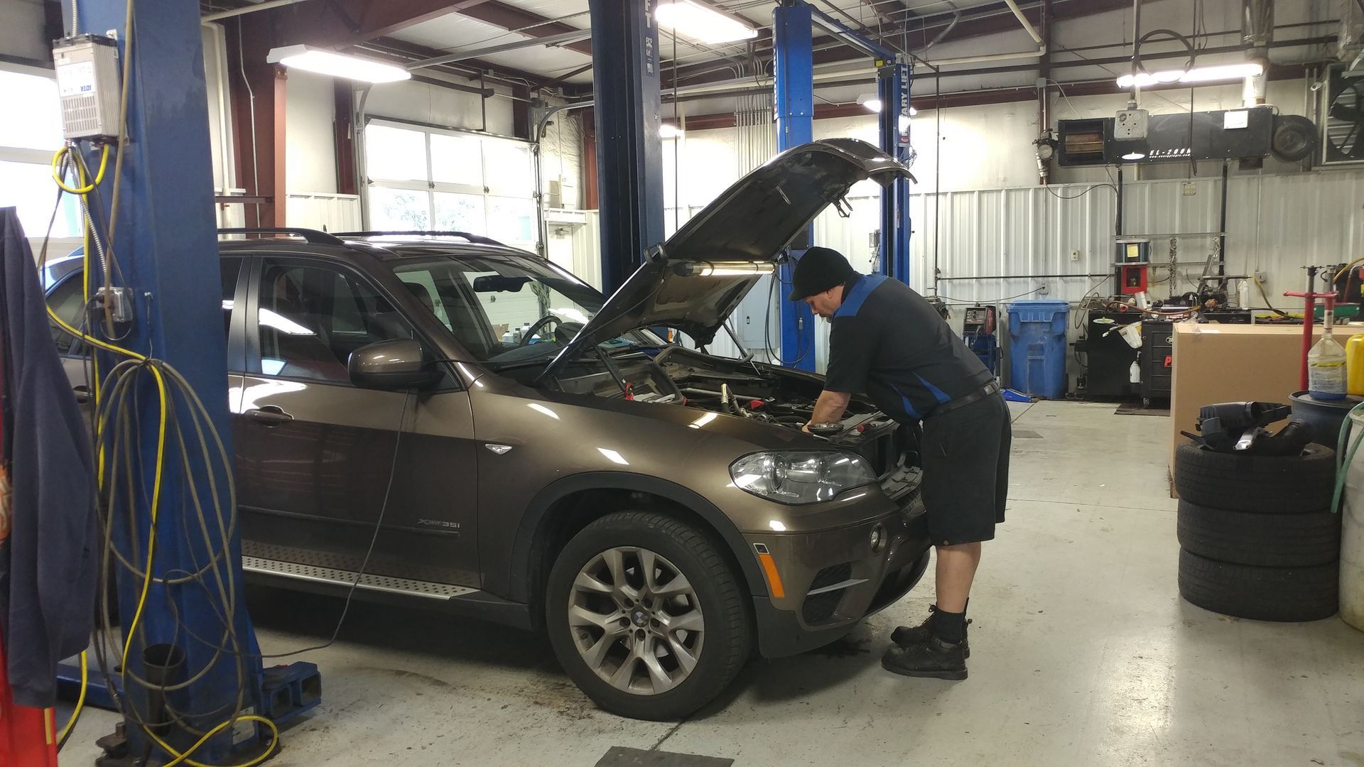 A man is working on the engine of a car in a garage. | Import Specialty Service