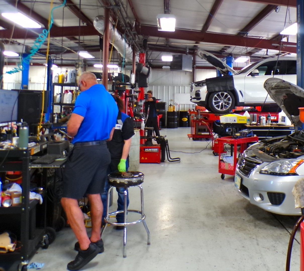 A man in a blue shirt is working in a garage | Import Specialty Service