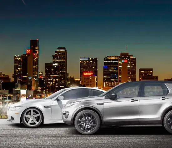 A white car with the hood open is on a lift in a garage. | Import Specialty Service