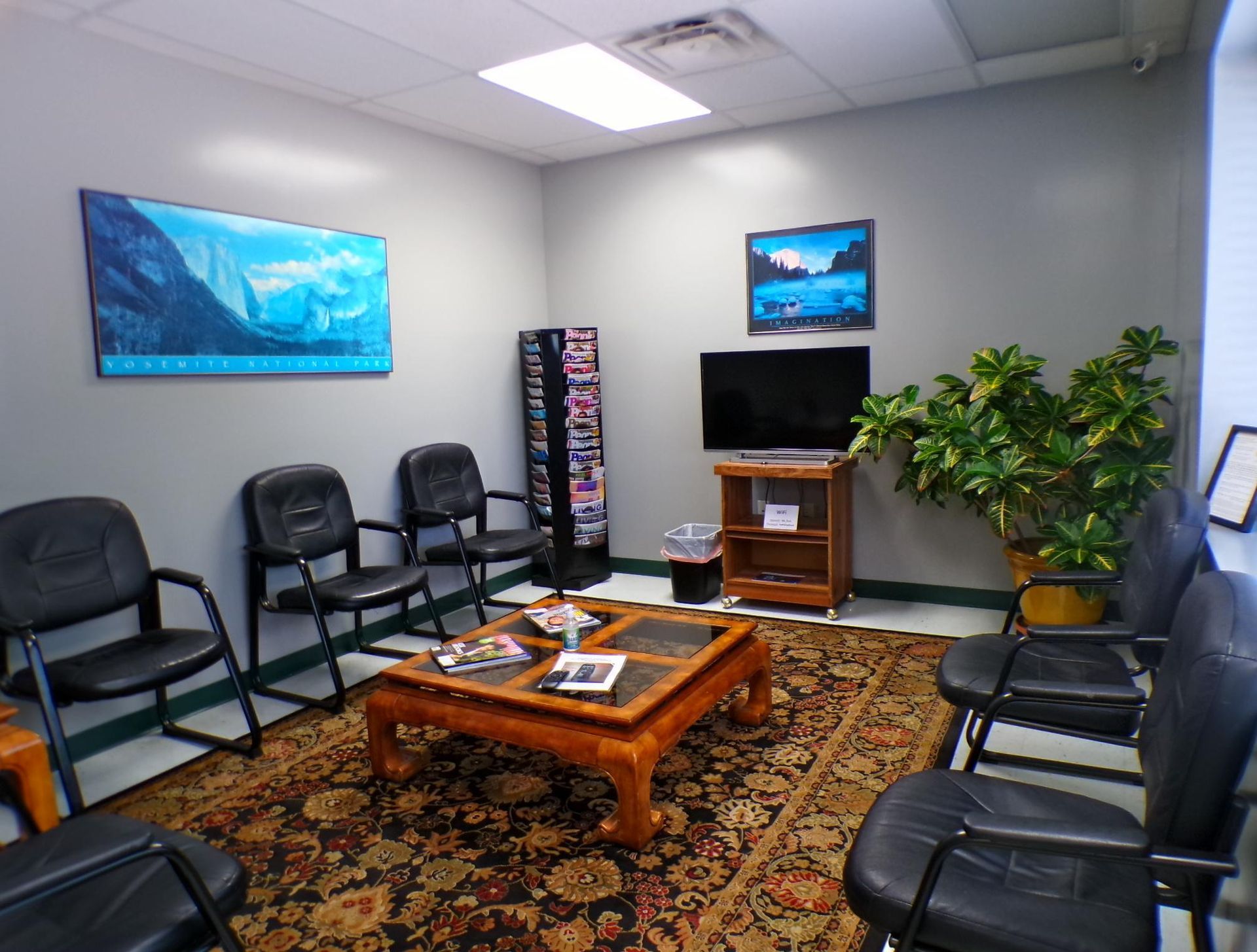 A waiting room with chairs , a coffee table and a television. | Import Specialty Service
