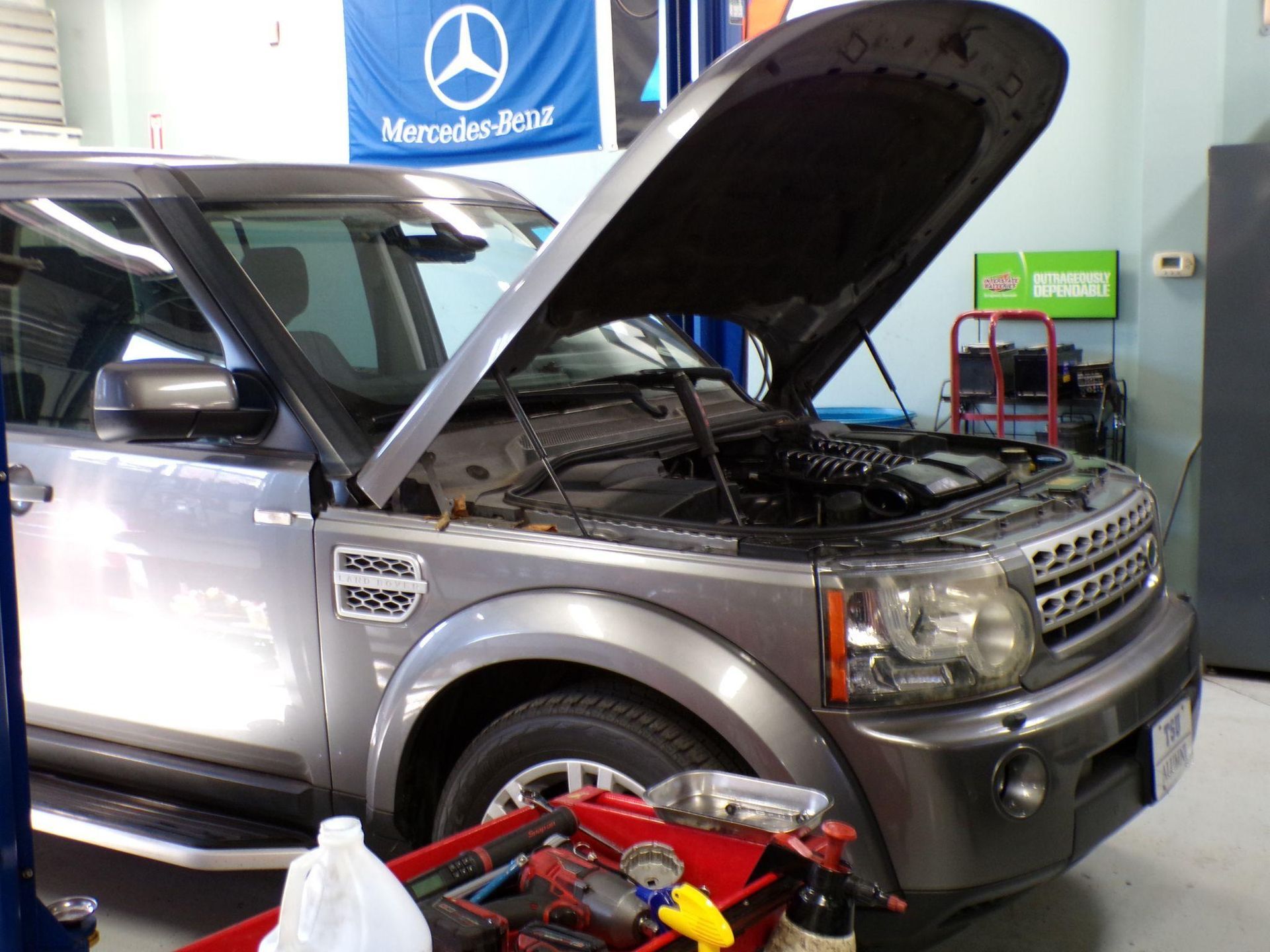A silver land rover with its hood open in a garage | Import Specialty Service