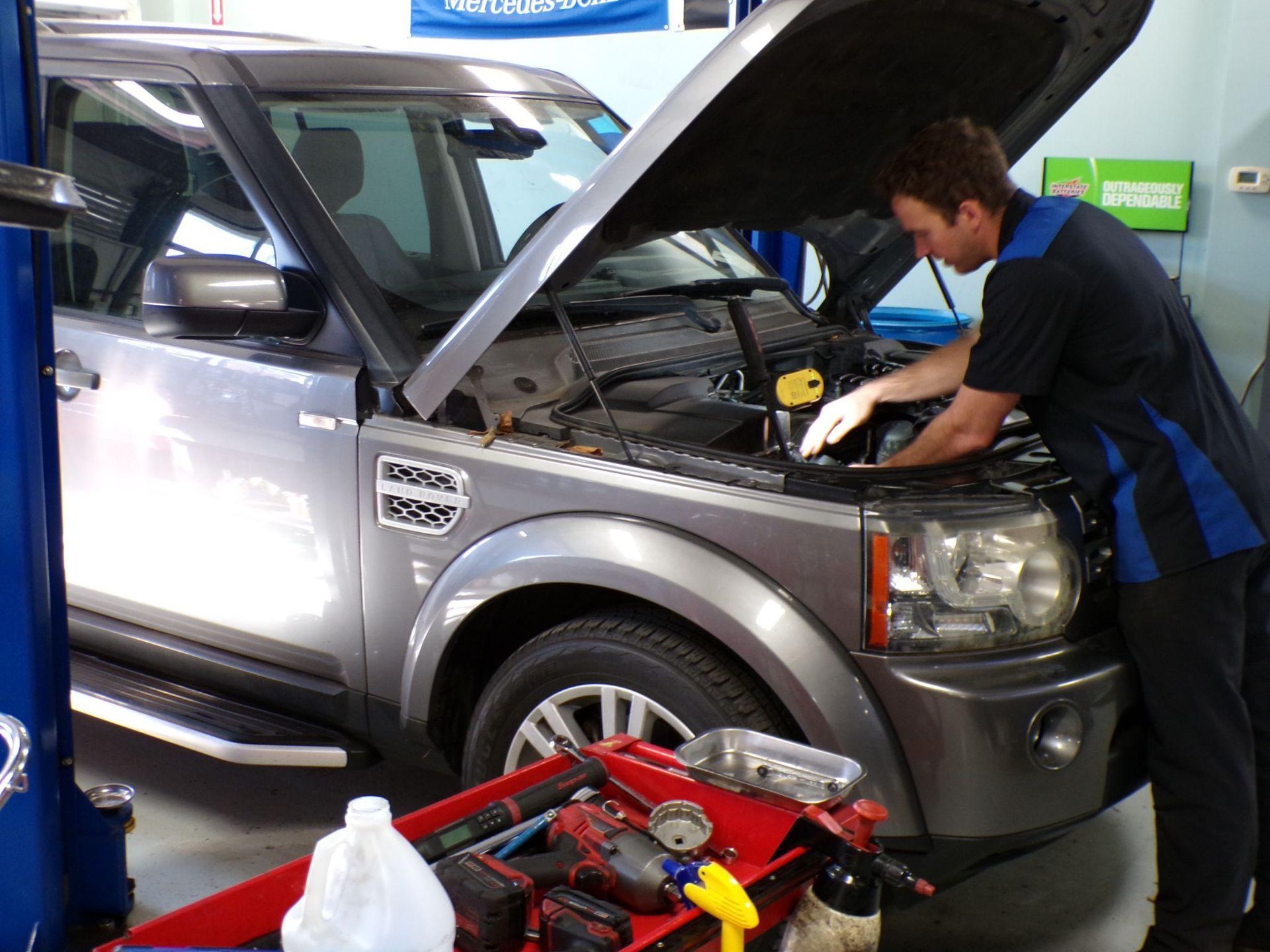 A man is working on a car with the hood open | Import Specialty Service