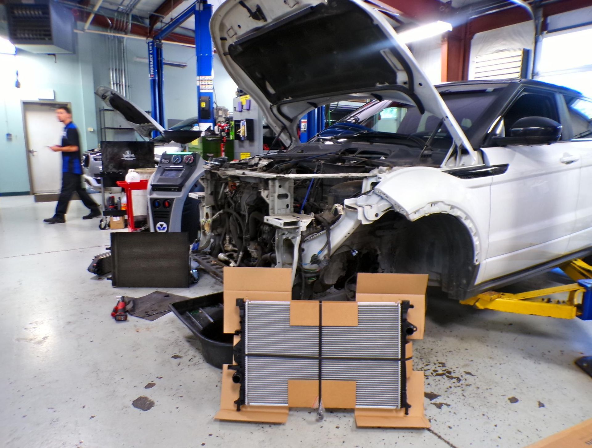 A white car is being worked on in a garage with the hood open | Import Specialty Service