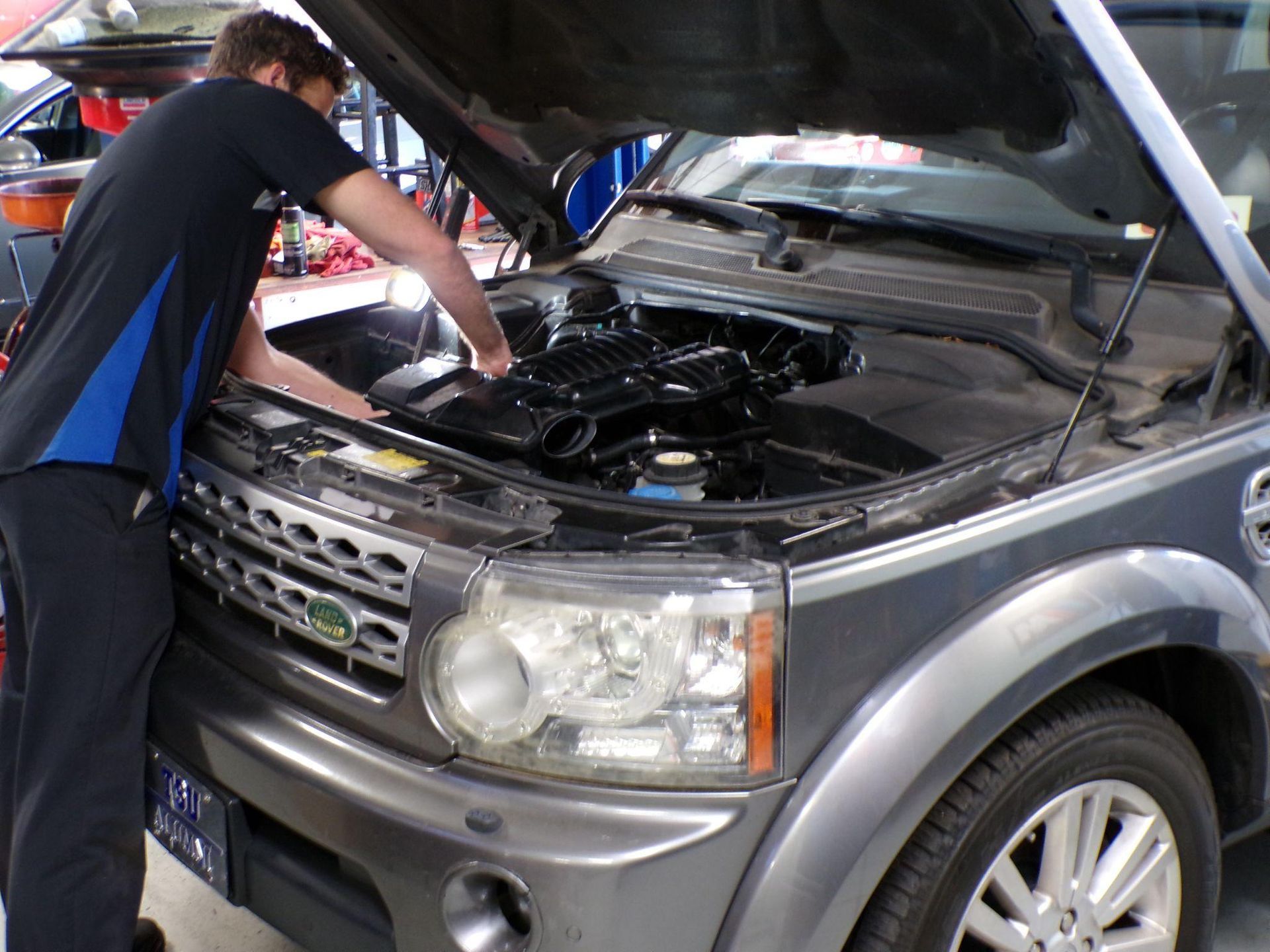 A man looking under the hood of a land rover | Import Specialty Service