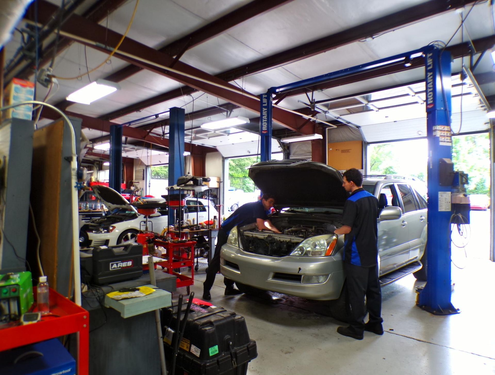 A group of men are working on a car in a garage. | Import Specialty Service