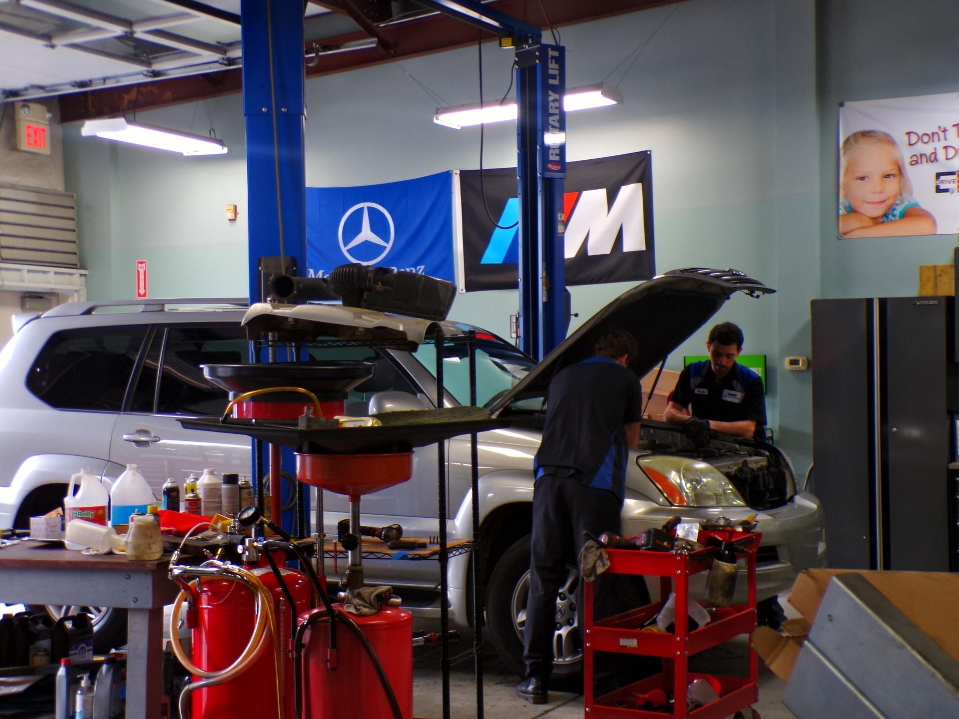 A man is working on a car with the hood up in a garage | Import Specialty Service