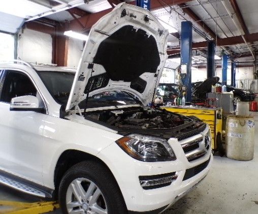 A white suv with the hood up in a garage | Import Specialty Service