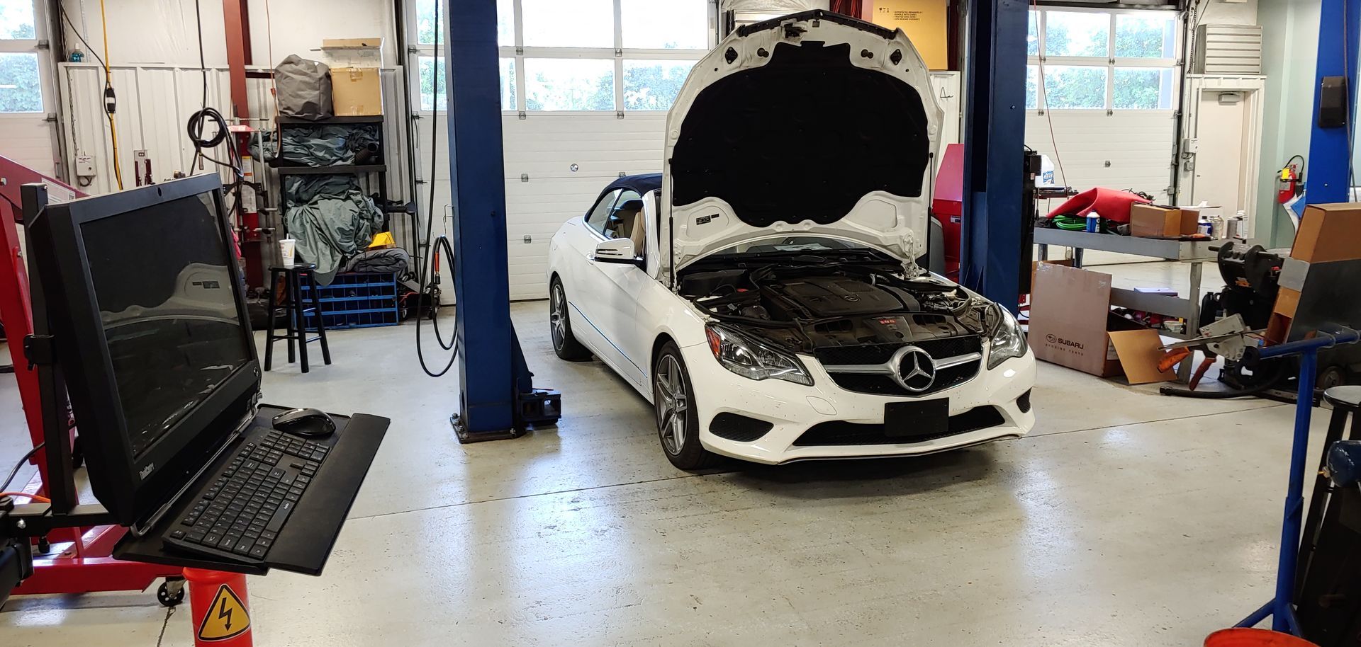 A white car is parked in a garage with its hood open. | Import Specialty Service