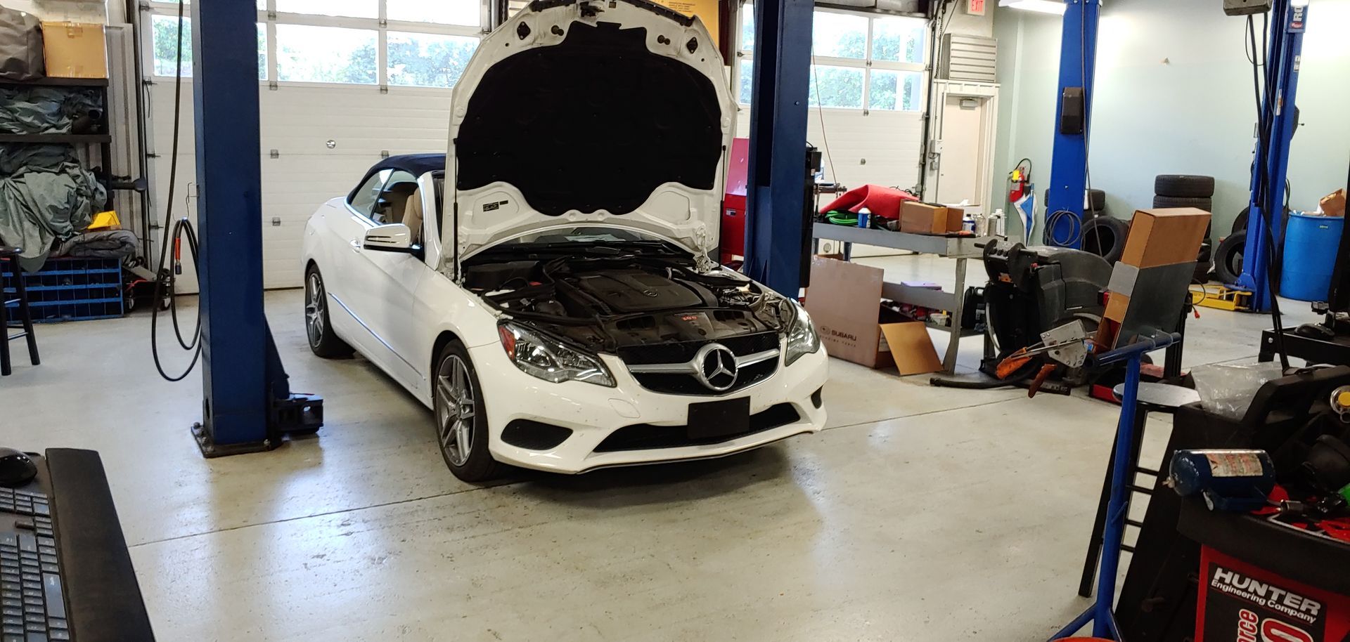 A white car with the hood up is parked in a garage. | Import Specialty Service