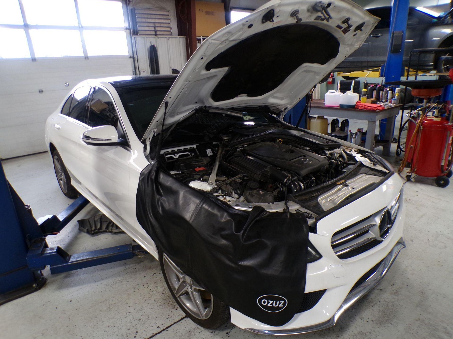 A white mercedes benz with its hood open in a garage. | Import Specialty Service