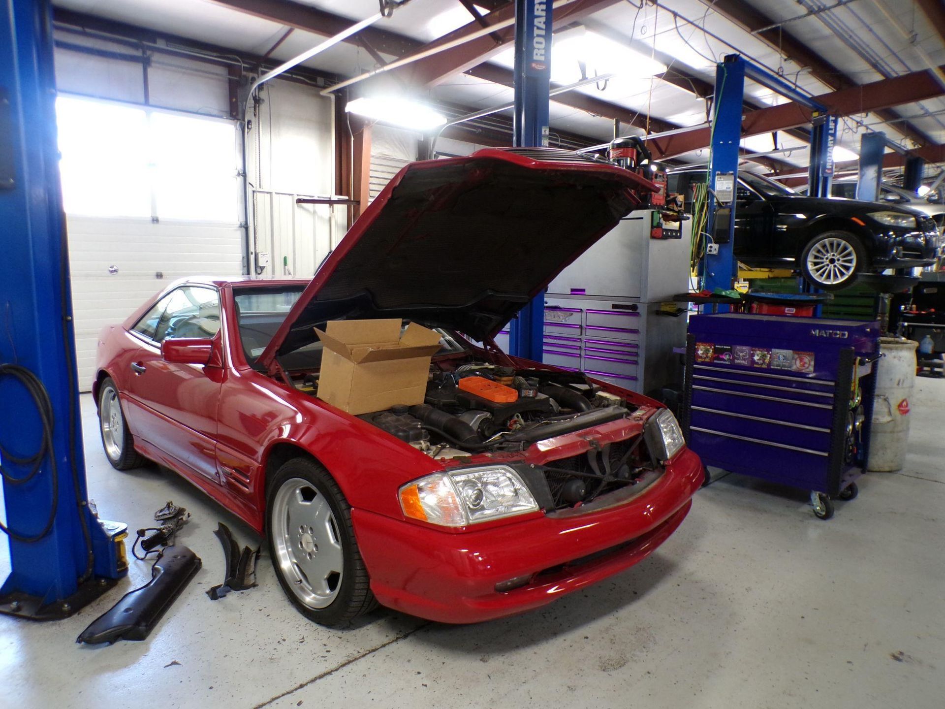A red car with the hood up in a garage | Import Specialty Service