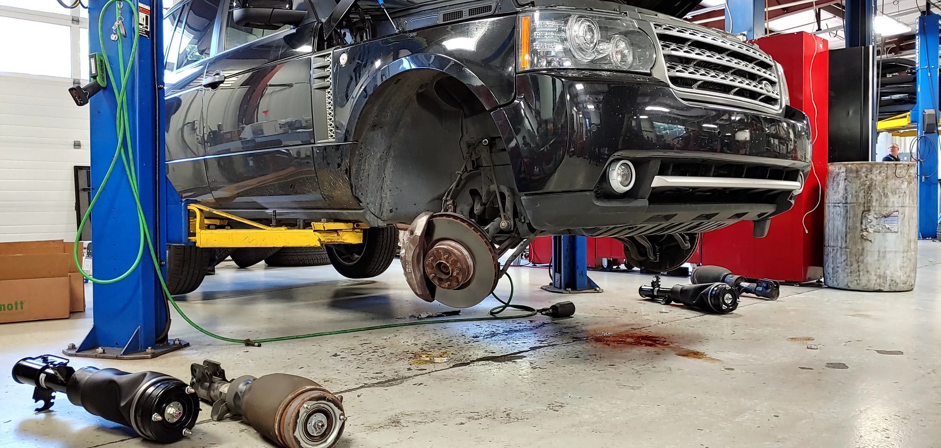 A car is sitting on a lift in a garage. | Import Specialty Service