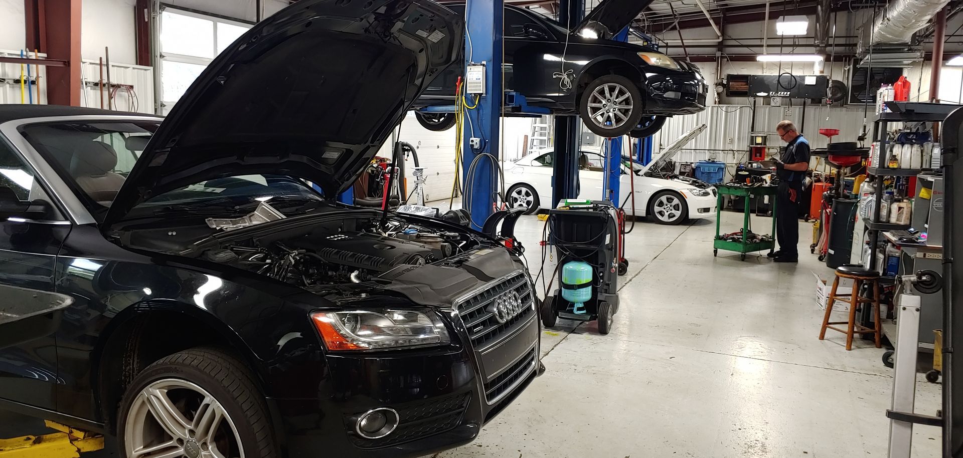 A black car is parked in a garage with its hood up. | Import Specialty Service