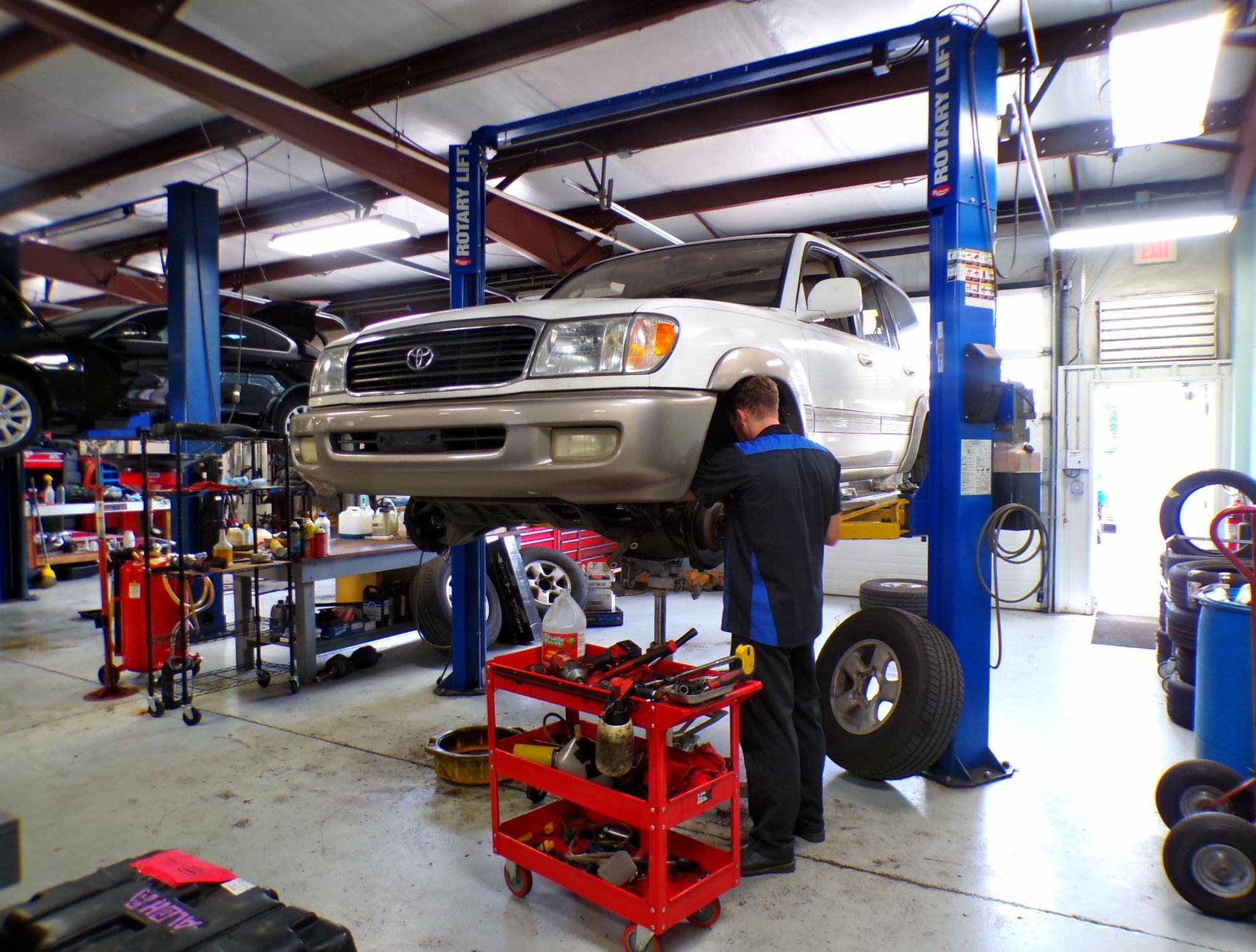 A man is working on a car on a lift in a garage | Import Specialty Service