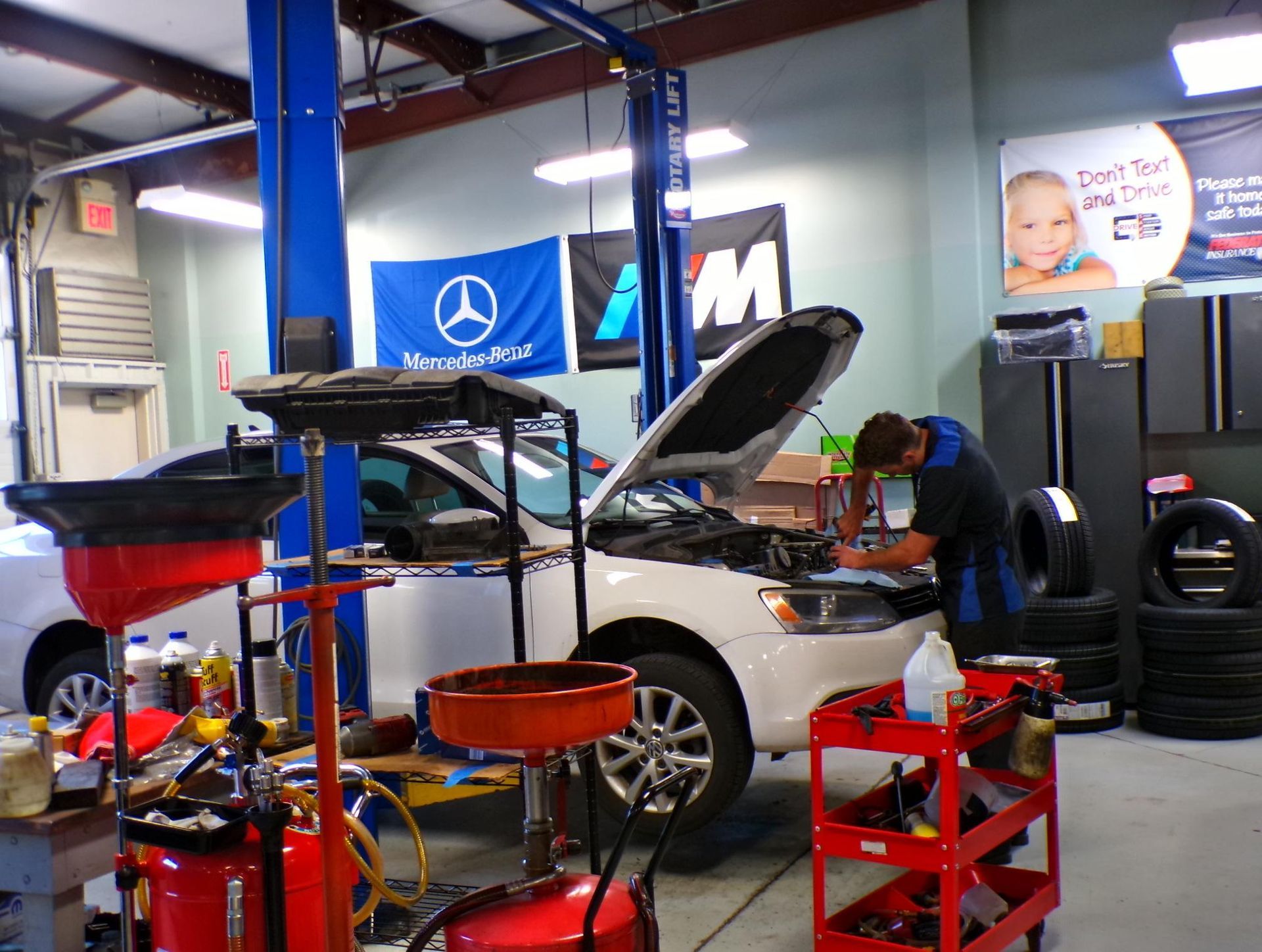 A man is working on a car in a garage with the hood open | Import Specialty Service