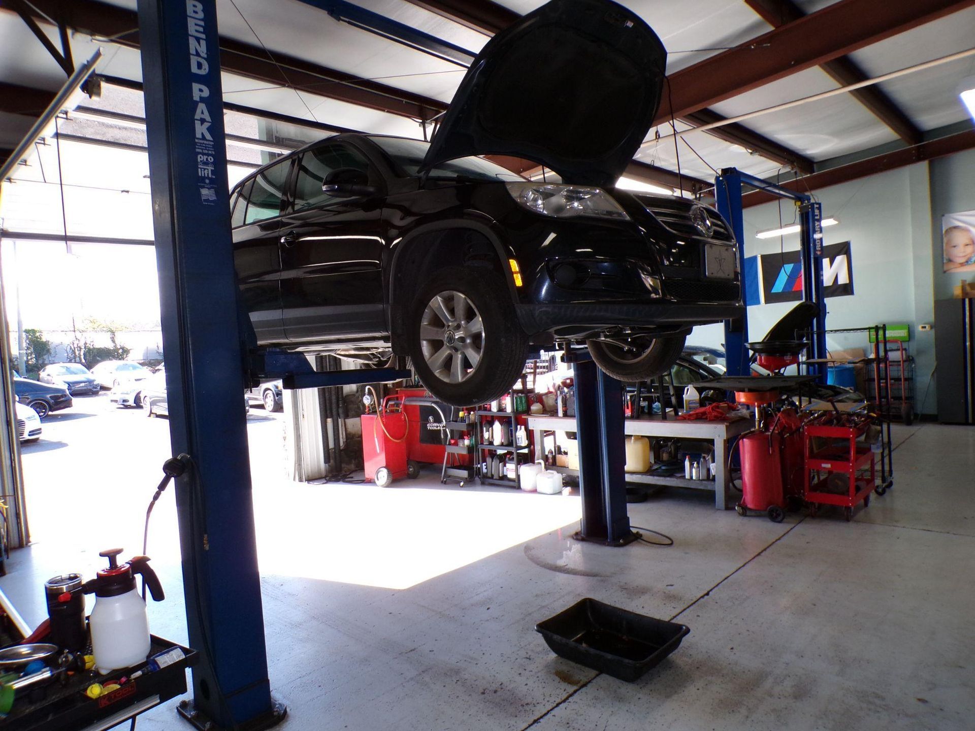 A car is on a lift in a garage with the hood up | Import Specialty Service