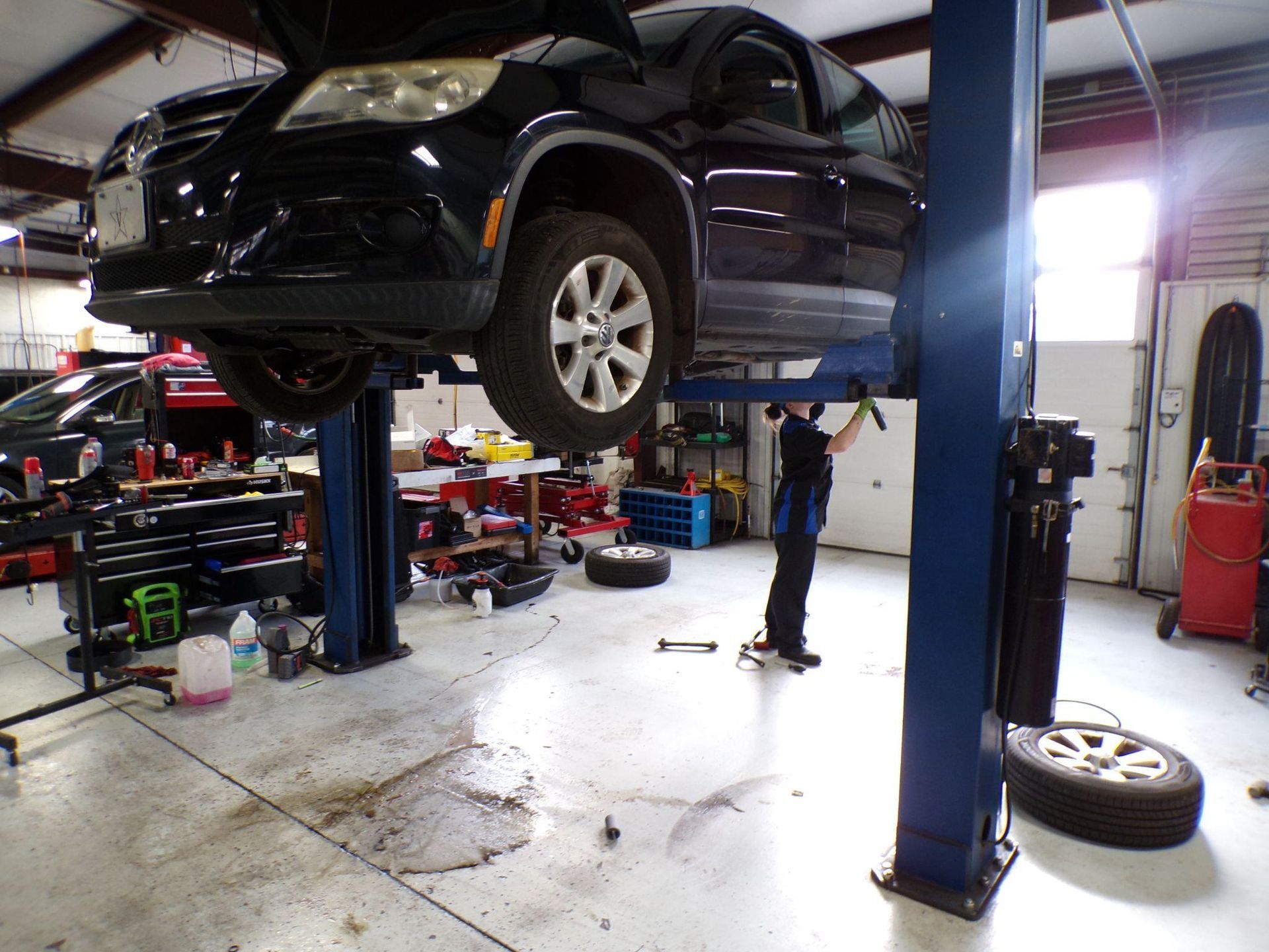 A black car is on a lift in a garage | Import Specialty Service