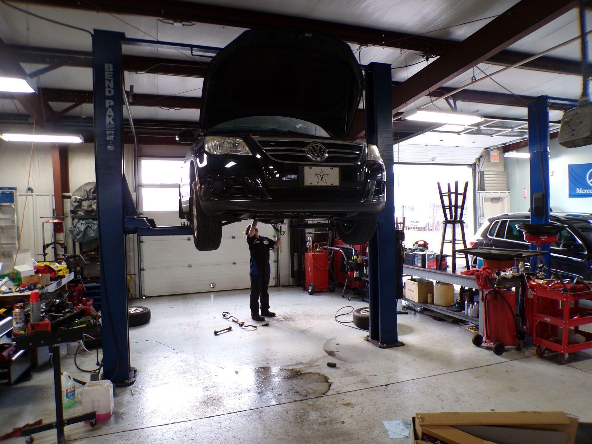 A man is working on a car on a lift in a garage. | Import Specialty Service