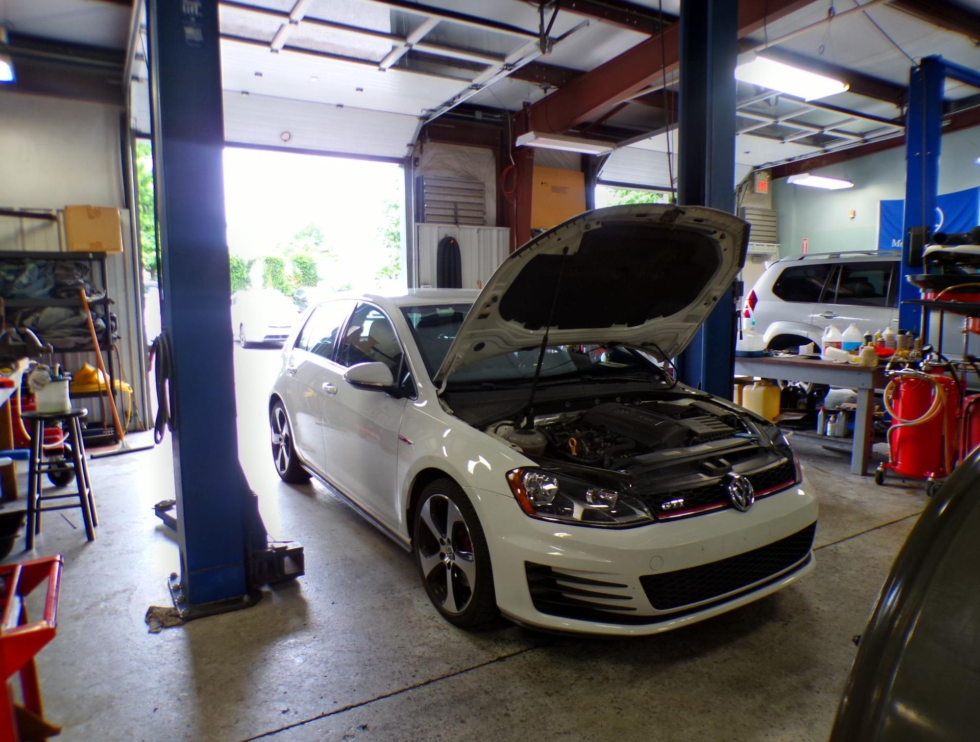 A white car with the hood up is parked in a garage. | Import Specialty Service