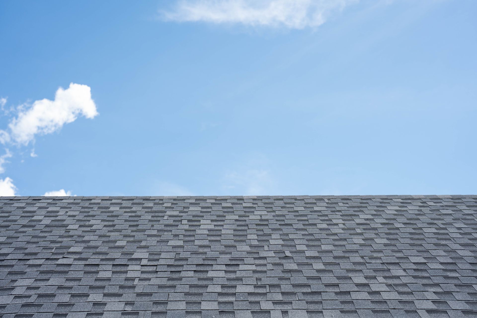 A man wearing a hard hat and safety vest is working on a roof.