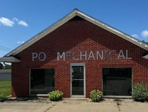 A man in a blue shirt is holding a clipboard and smiling.