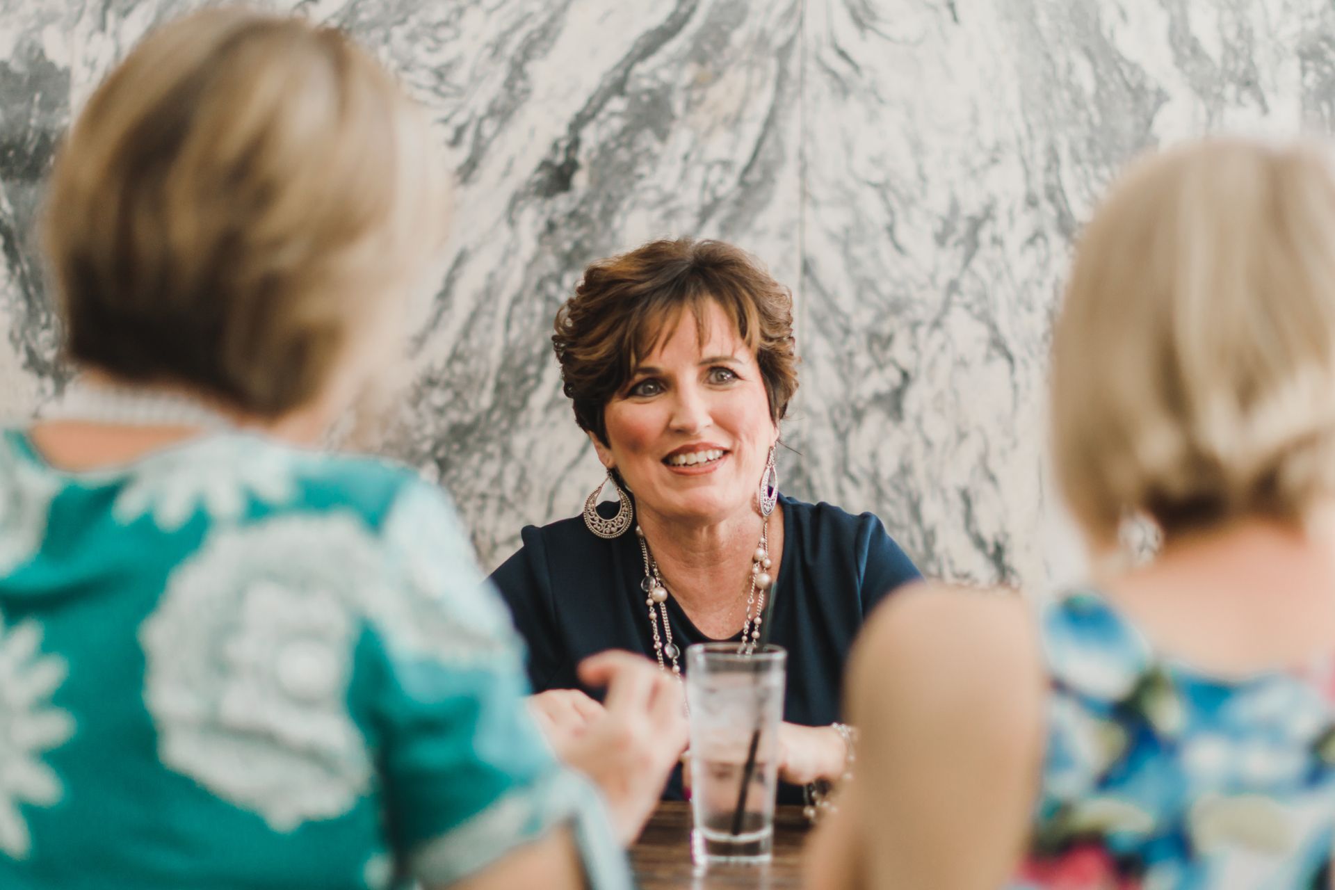 A group of women are sitting at a table talking to each other.