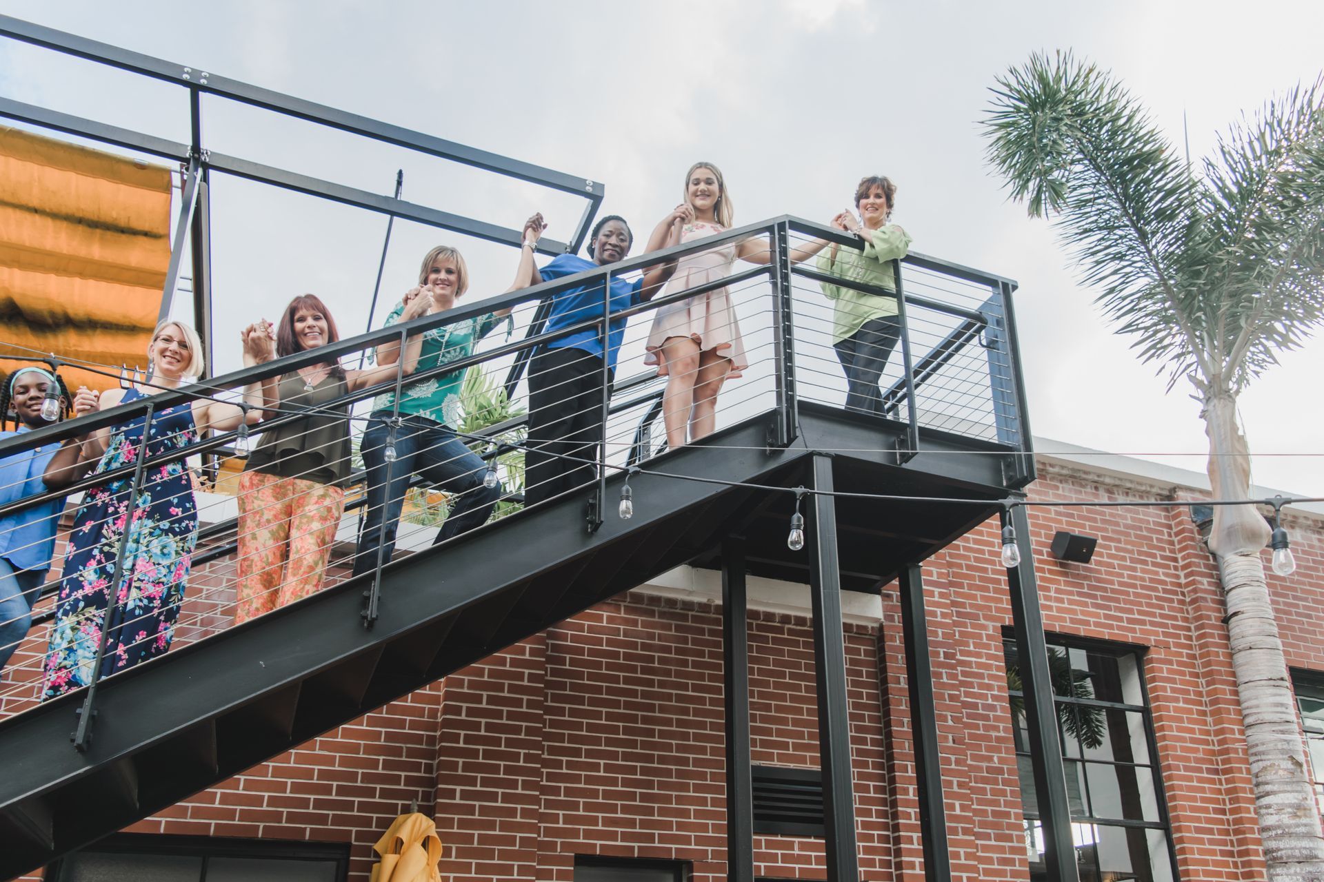 A group of women are posing for a picture in front of a brick building.