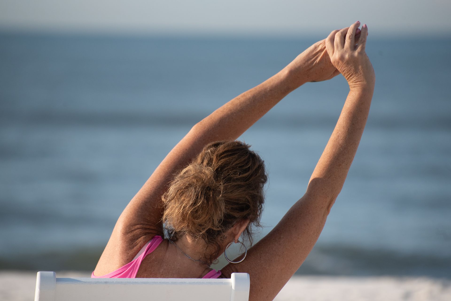 A woman is sitting in a lotus position on the beach.