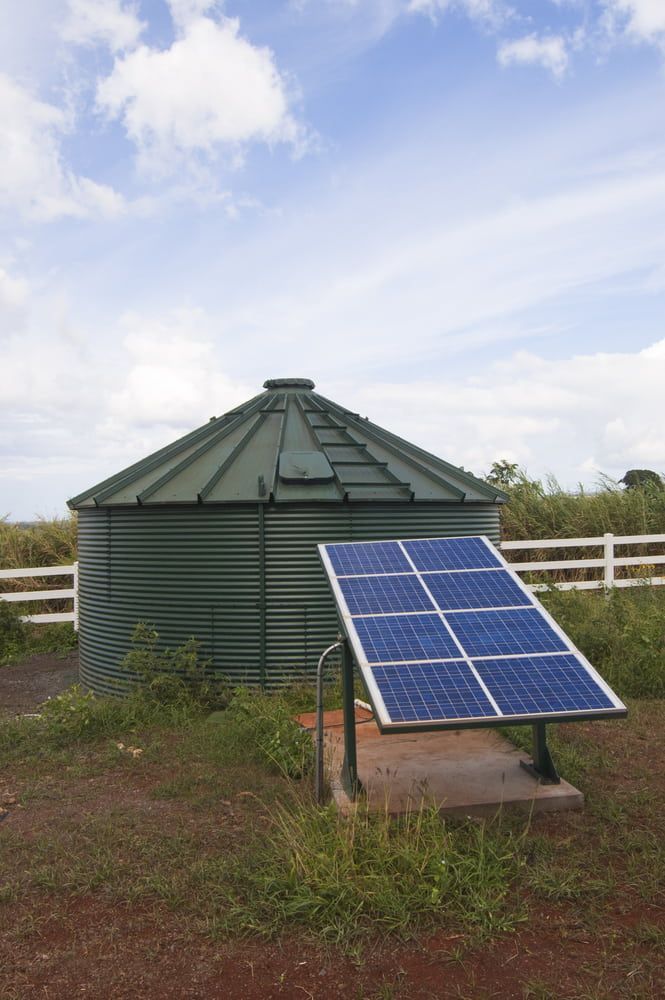 A Solar Panel is Sitting in Front of a Water Tank — Hastings Water Care In Redbank, NSW
