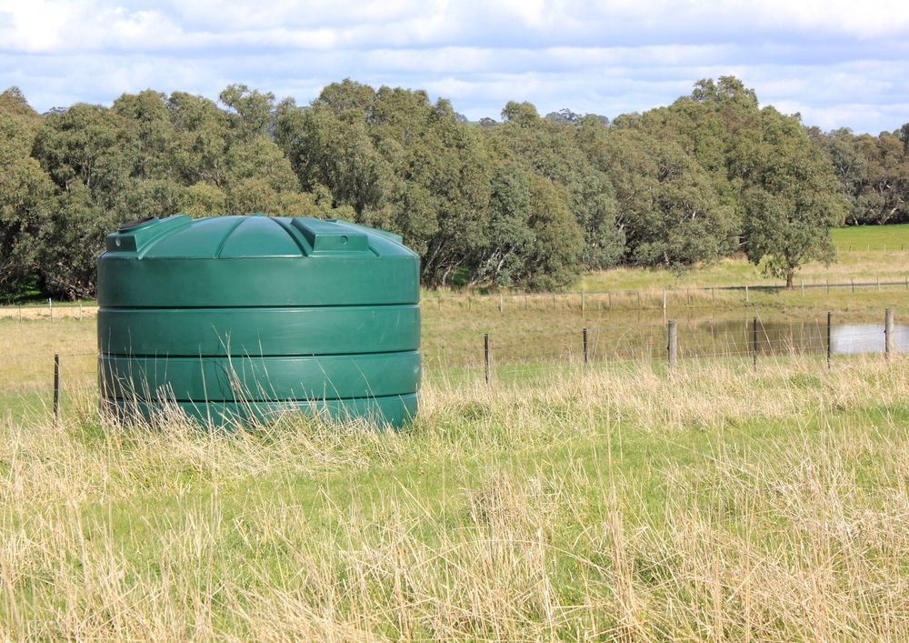 A Green water tank sitting in a grassy field — Hastings Water Care In Redbank, NSW