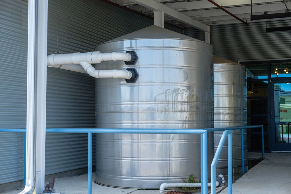 Large Metallic Water Tanks With Connected White Pipes — Hastings Water Care In Redbank, NSW