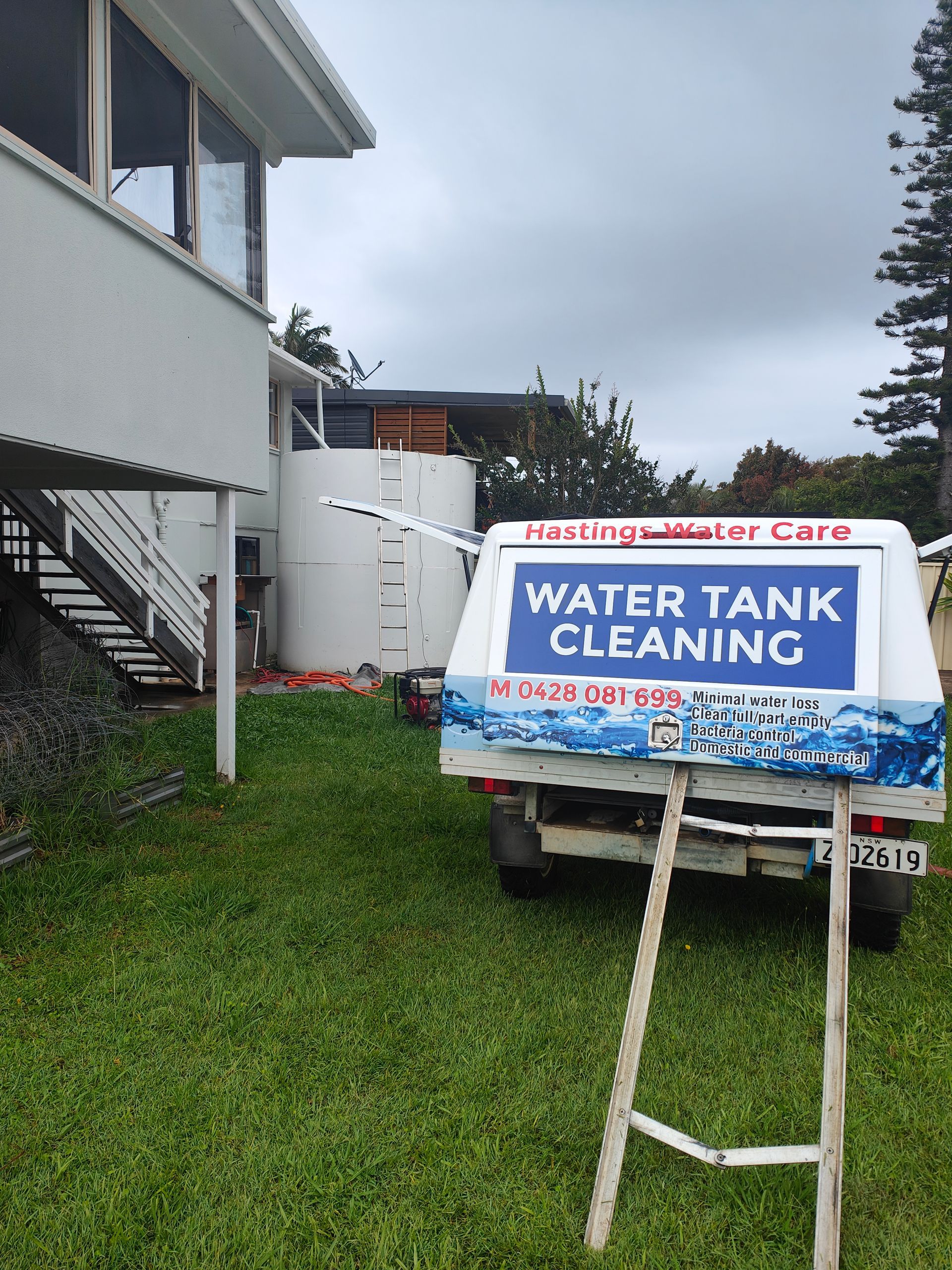A branded work vehicle that is parked on grass in front of a water tank - Hastings Water Care in Port Macquarie NSW