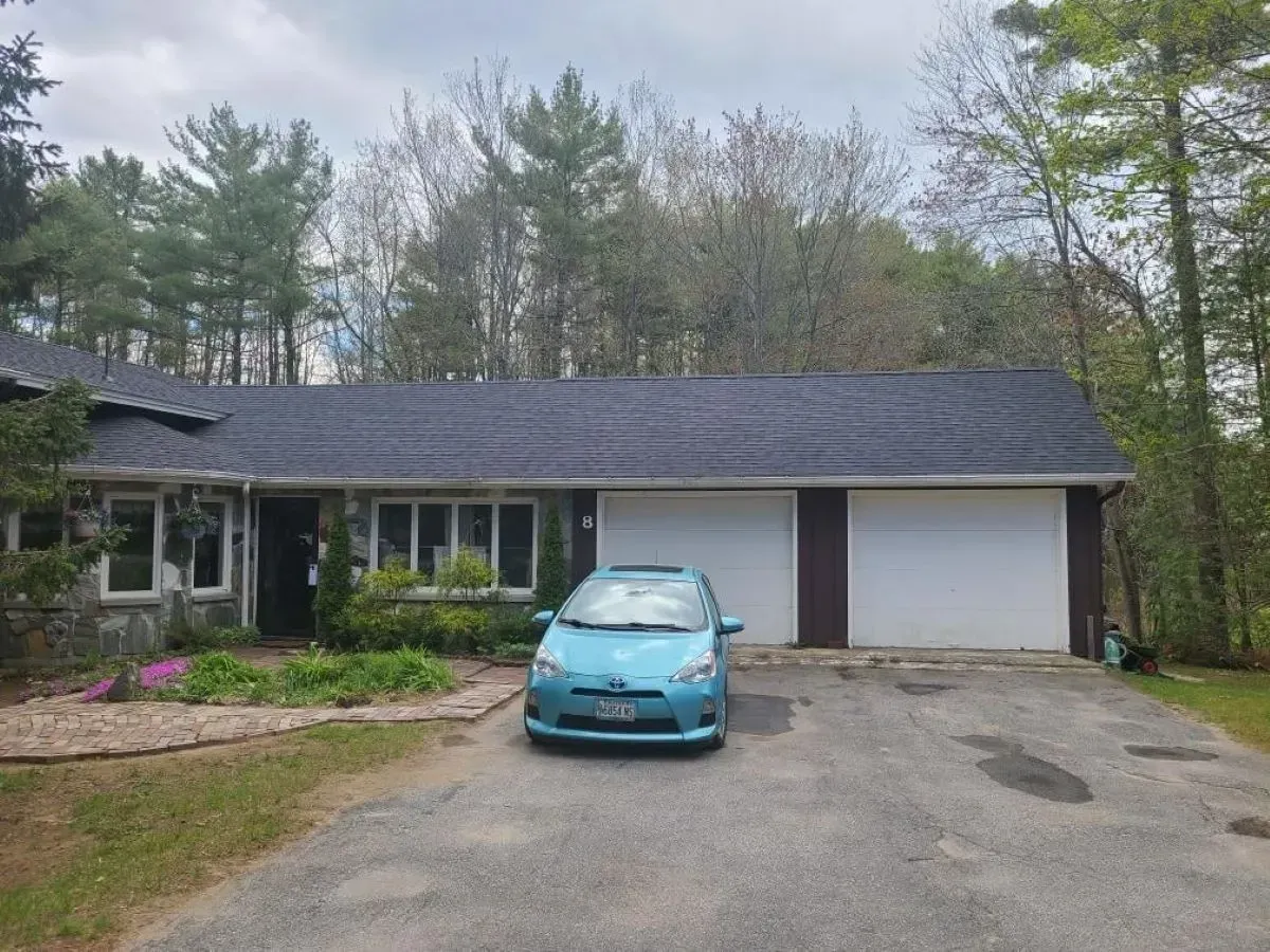 A blue car is parked in front of a house.